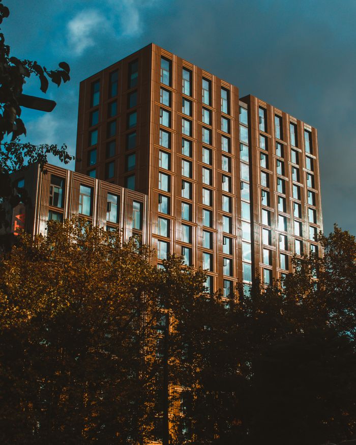 services-01 Modern high-rise building in Leeds, UK, captured with a dynamic low-angle view, framed by trees.