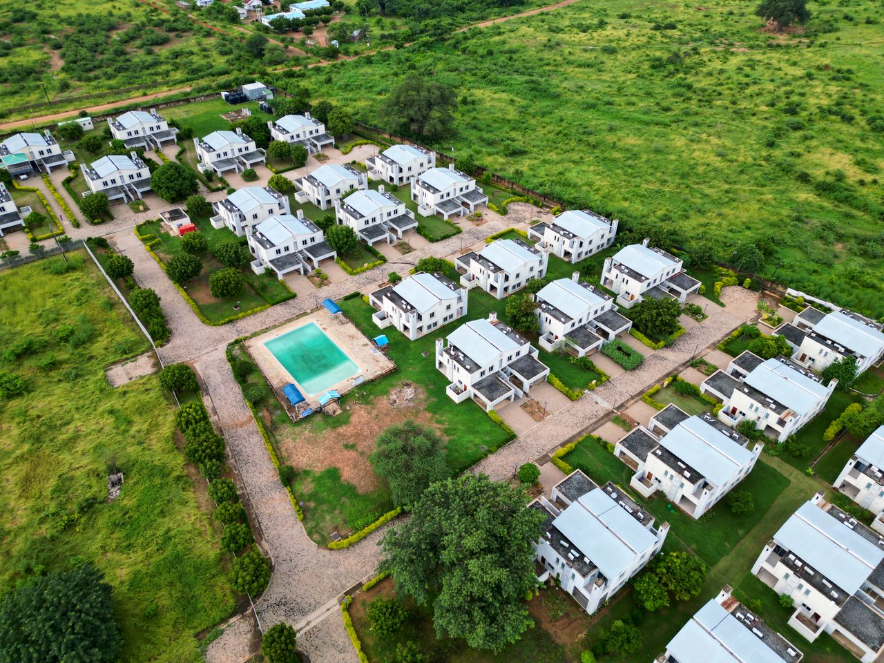 services-03 Aerial photograph of a modern housing estate with a communal pool, surrounded by lush greenery.
