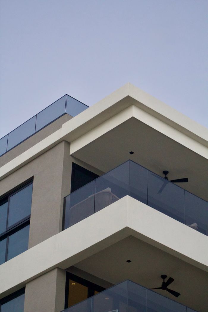 Contemporary apartment building with glass balconies against a clear sky.