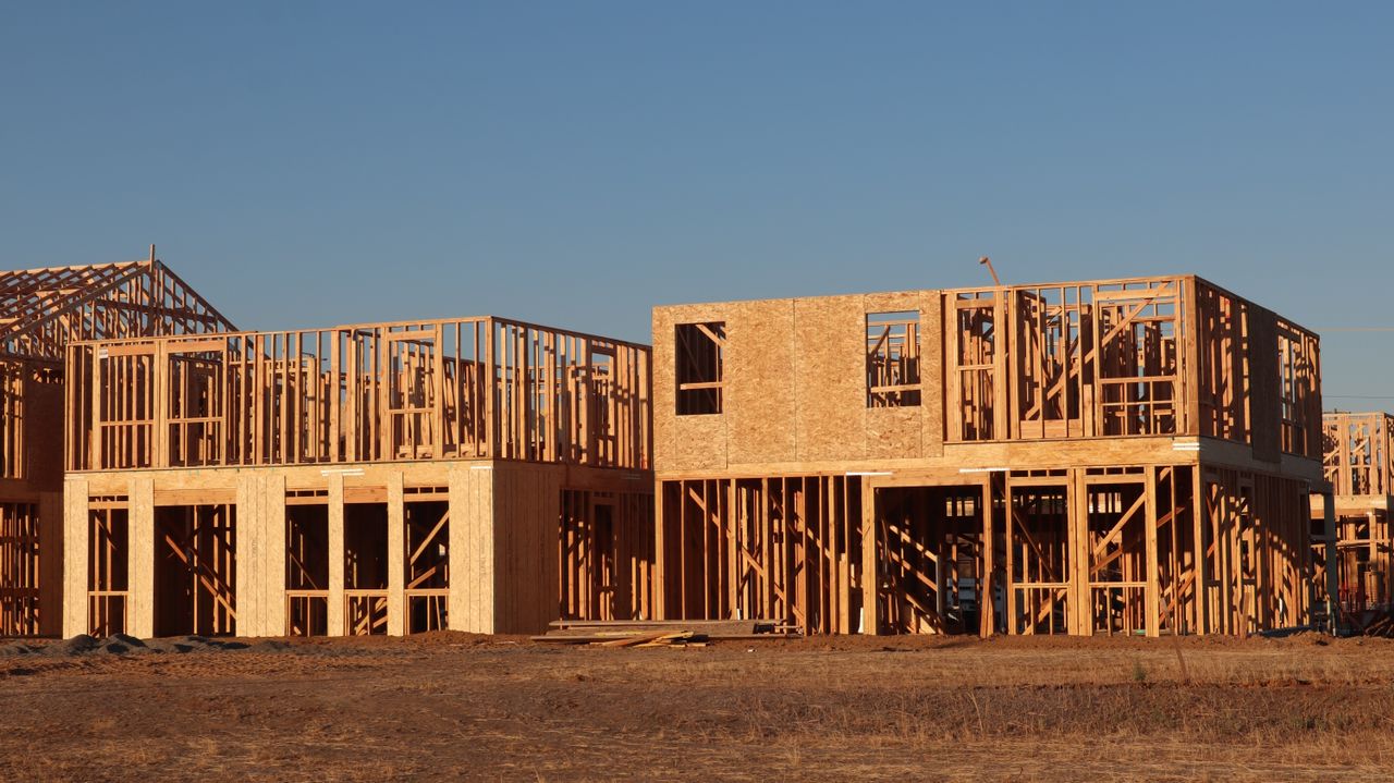 about-img Wooden frames of new homes under construction in Elk Grove, California, during daylight.
