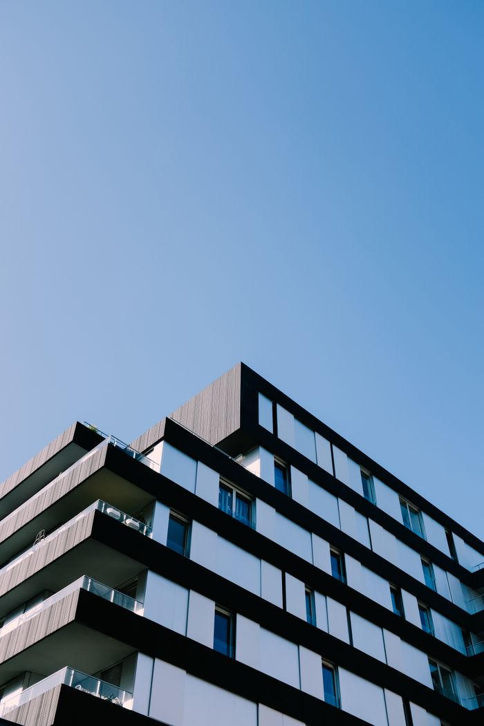 services-img Low angle view of a modern apartment building with sleek design against a clear blue sky.